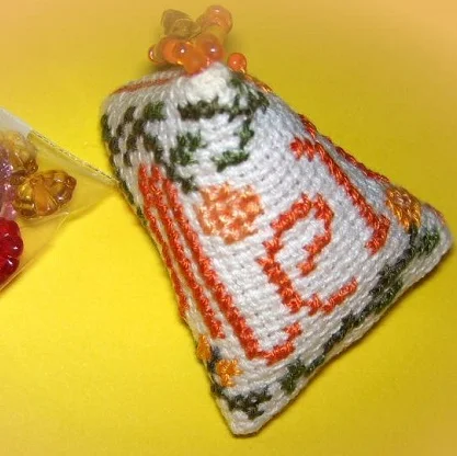 Berlingot brodé au point de croix sur toile blanche, motif rouge et vert, pointe ornée de perles orange