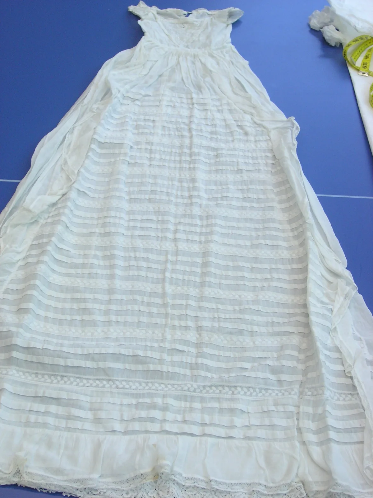 Robe de baptême ancienne en broderie blanche fine posée à plat, exemple d'inspiration pour un projet whitework