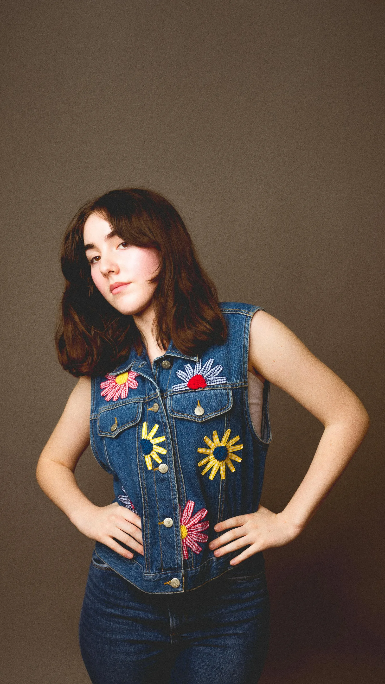 Veste en jean sans manches ornée de motifs floraux brodés en appliqué, exemple de broderie décorative sur un support résistant