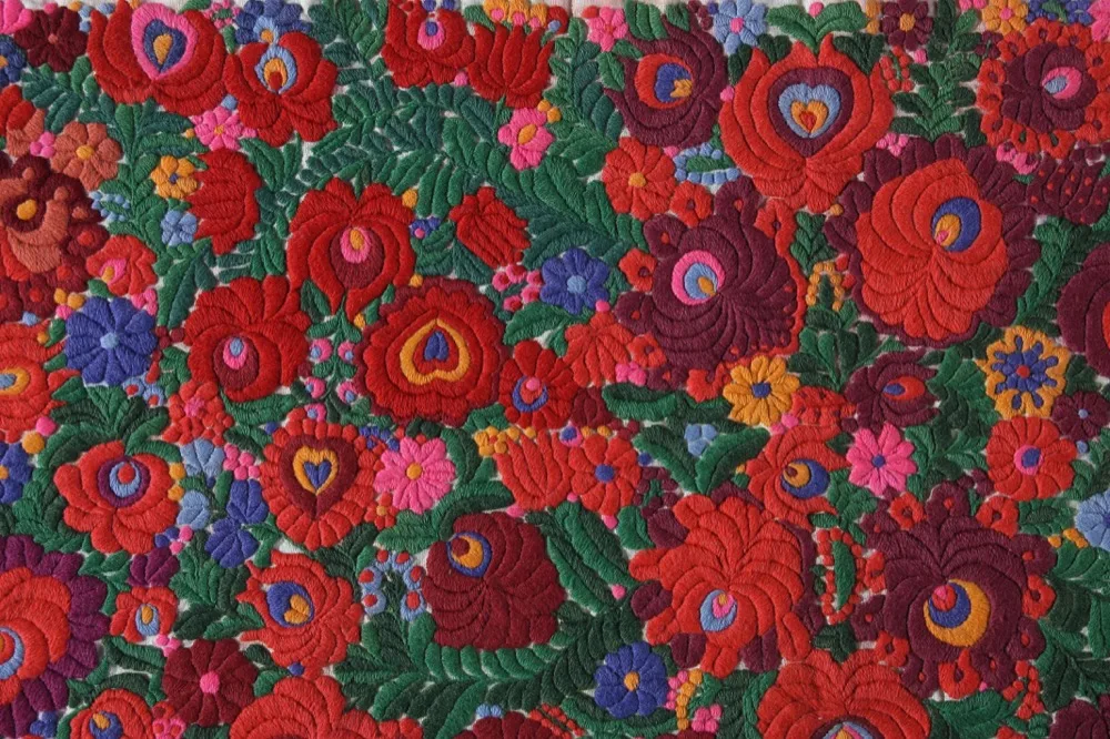 Détail macro d'une broderie hongroise traditionnelle aux motifs floraux rouges et noirs