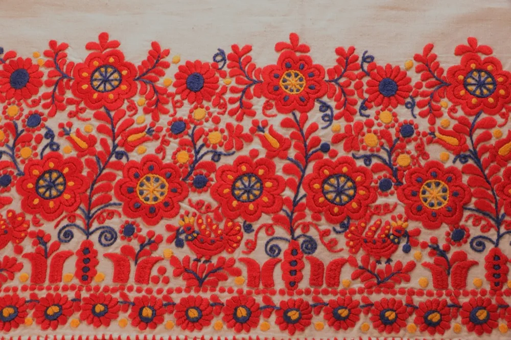 Broderie hongroise traditionnelle aux motifs floraux rouges et bleus sur fond clair