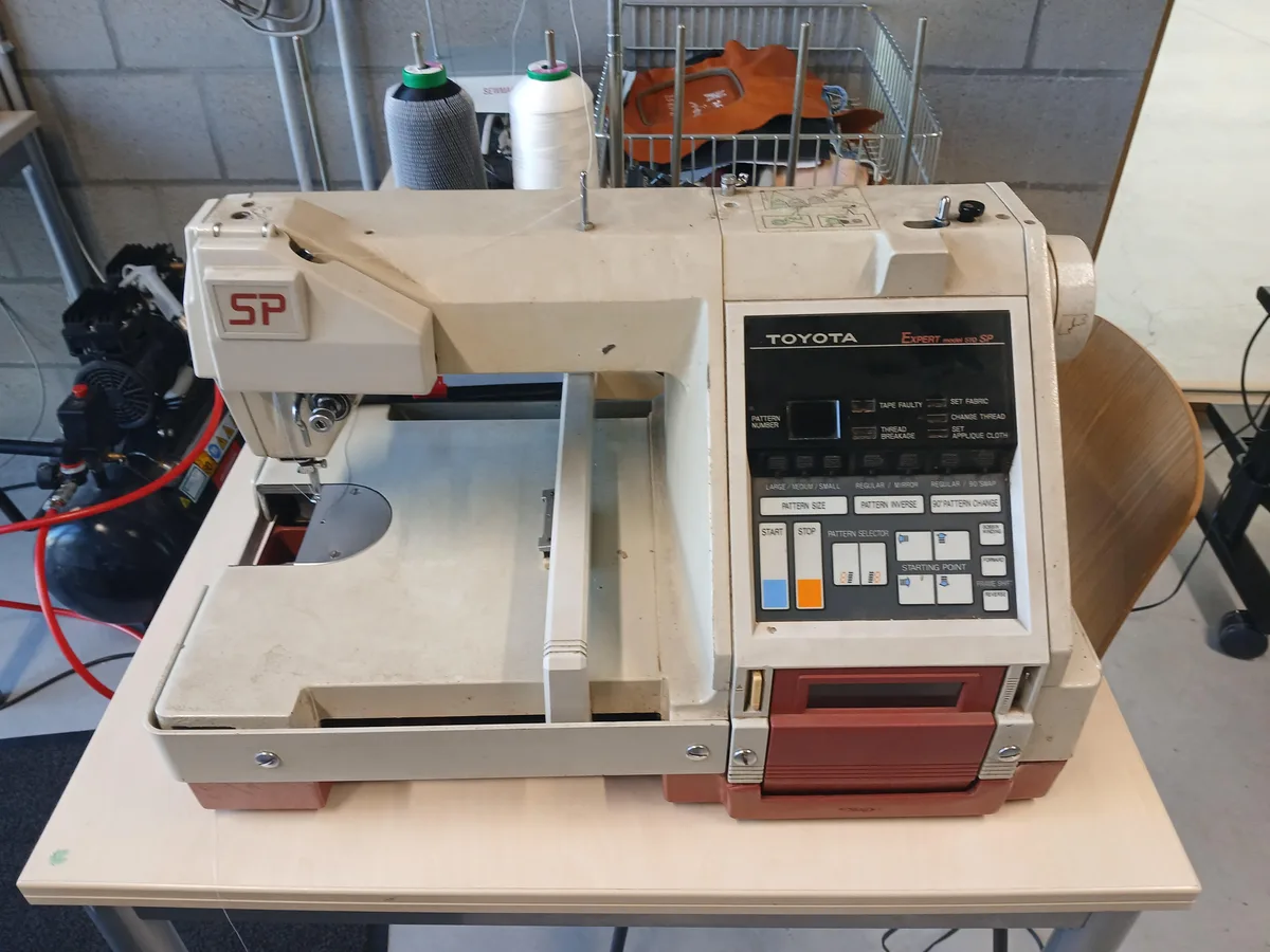 Machine à broder domestique avec bobines de fils colorés et écran de programmation des motifs