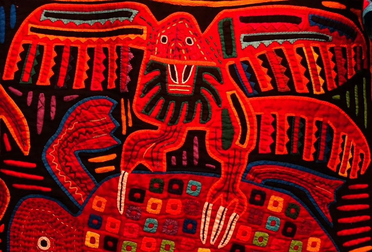 Mola kuna représentant un oiseau stylisé aux couleurs vives sur fond noir et rouge
