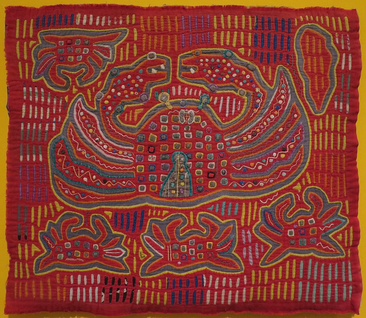 Mola kuna coloré représentant un crabe stylisé entouré de motifs géométriques en appliqué inversé