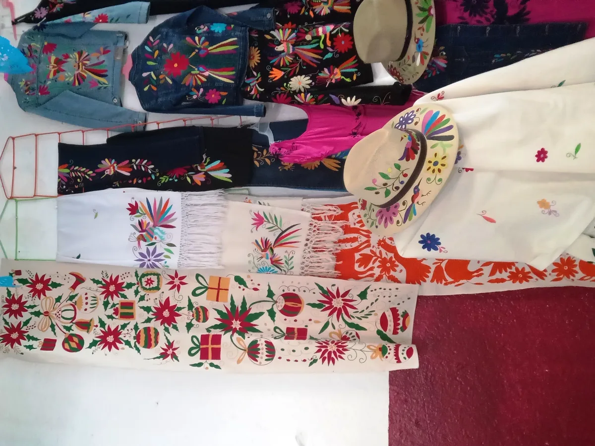Vêtements et accessoires brodés de motifs Otomi colorés présentés dans une boutique artisanale
