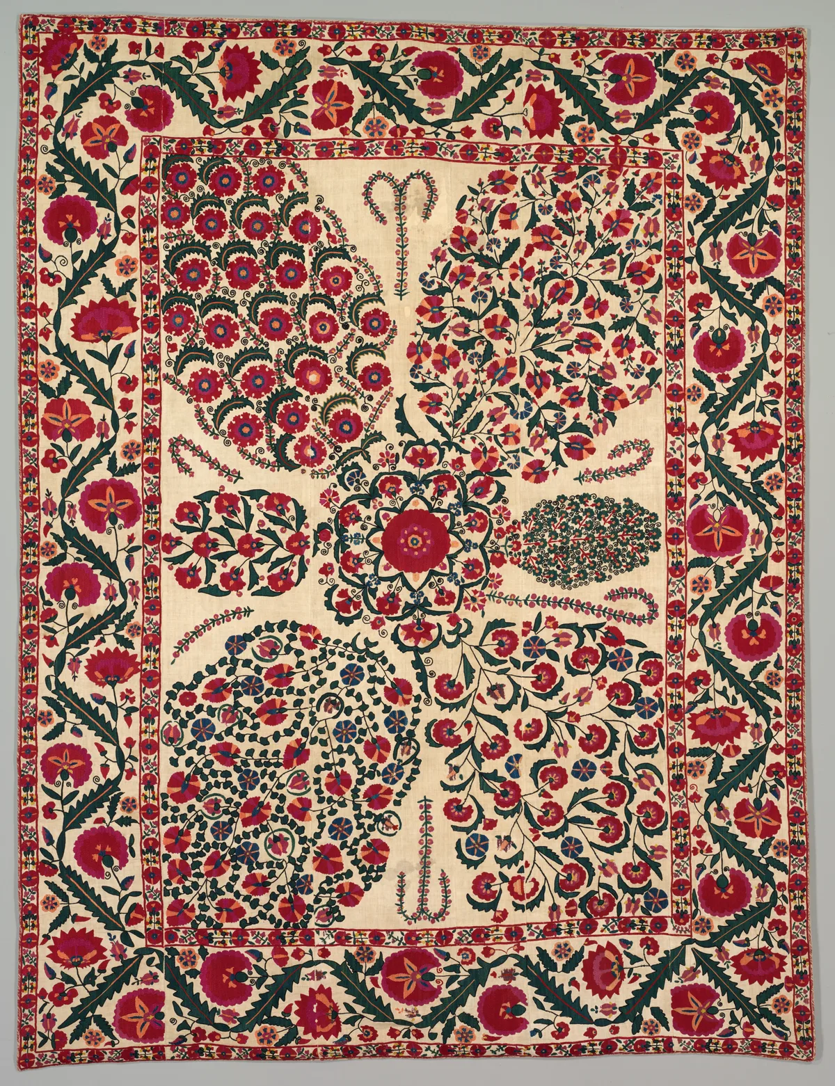 Détail de suzani ancien aux motifs de grenades et de fleurs stylisées sur fond ivoire