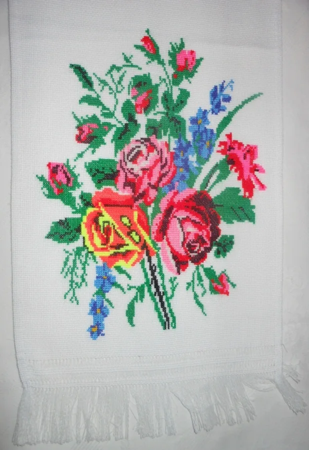 Broderie florale au point de croix représentant un bouquet de roses colorées sur linge brodé