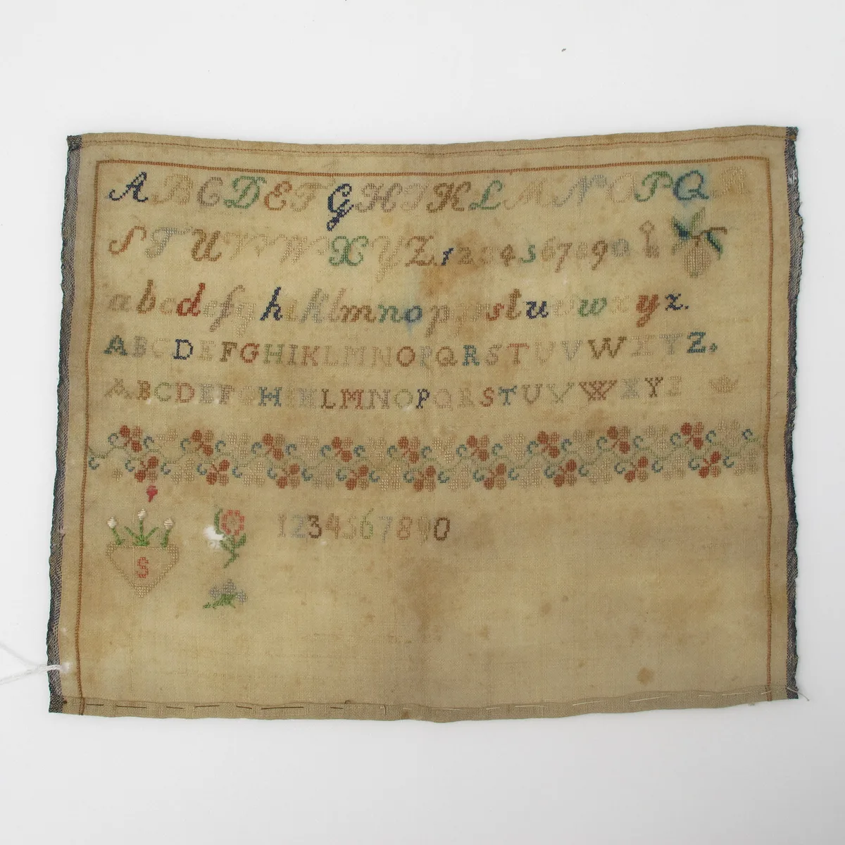 Sampler historique point de croix avec bordure florale botanique, alphabets et motifs végétaux sur toile ancienne
