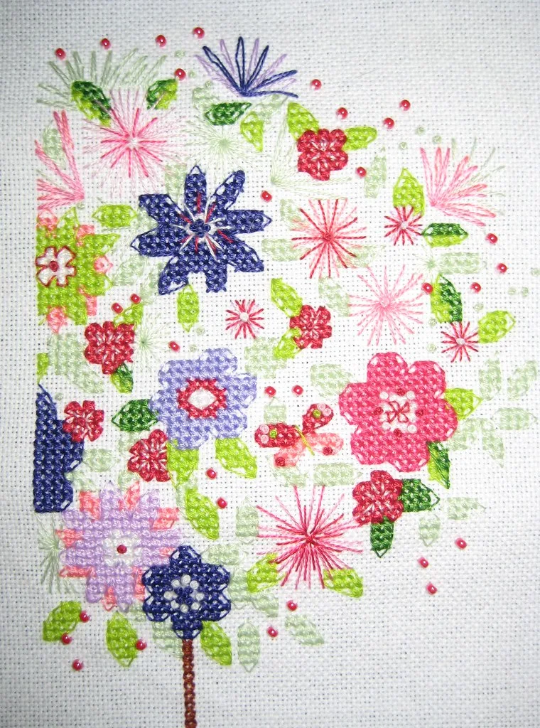 Résultat d'une broderie végétale en point de croix : topiaire fleuri avec roses, anémones et feuilles vertes sur toile Aïda