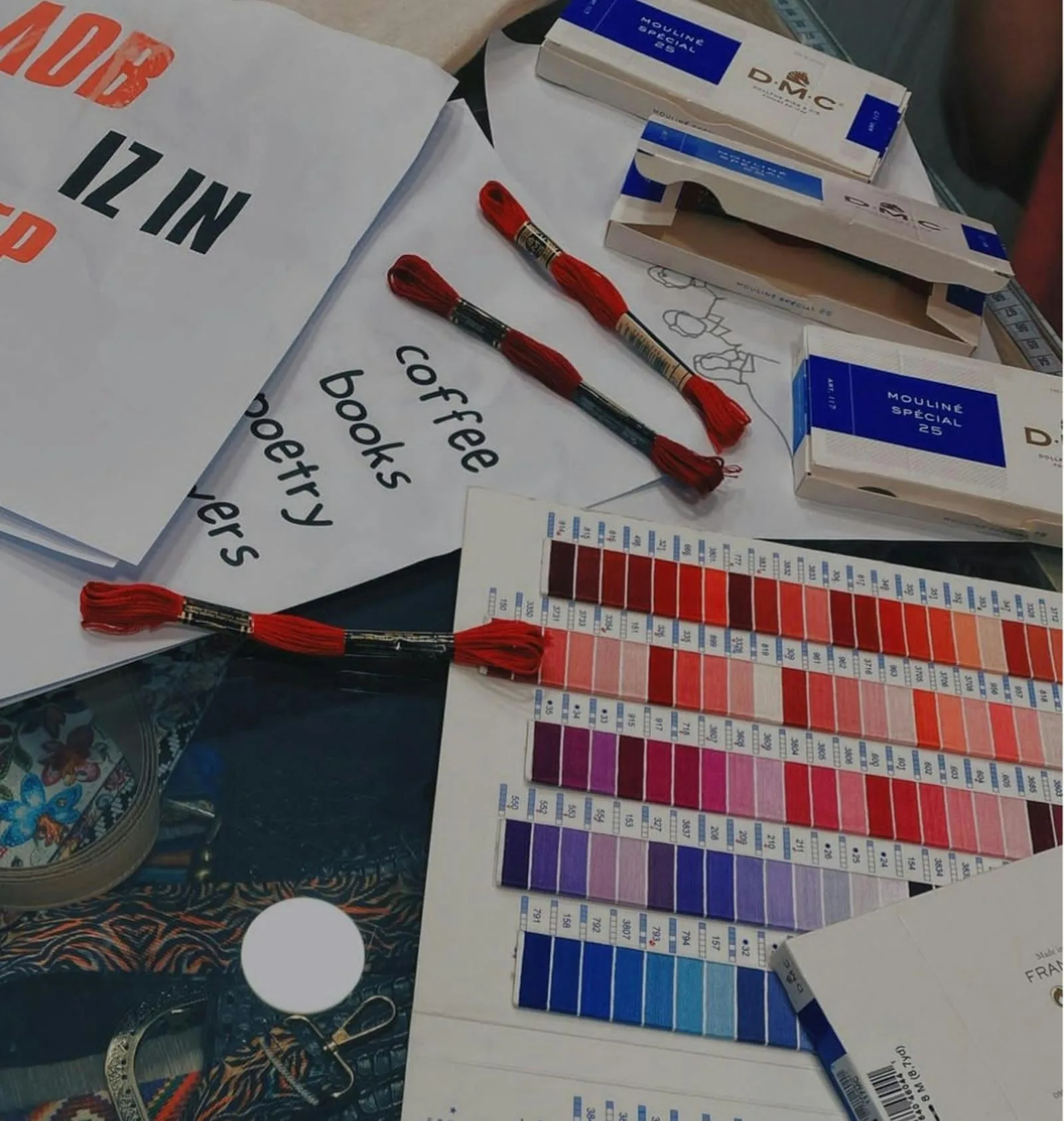 Fils à broder rouges et accessoires de couture posés sur un bureau créatif, ambiance inspiration pour cadeau brodé homme