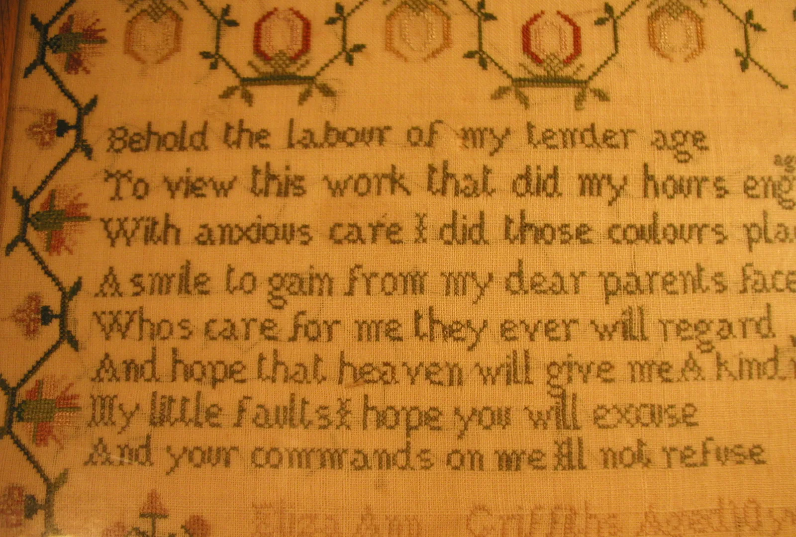 Sampler brodé ancien encadré avec texte et motifs, exemple de résultat fini en broderie comptée