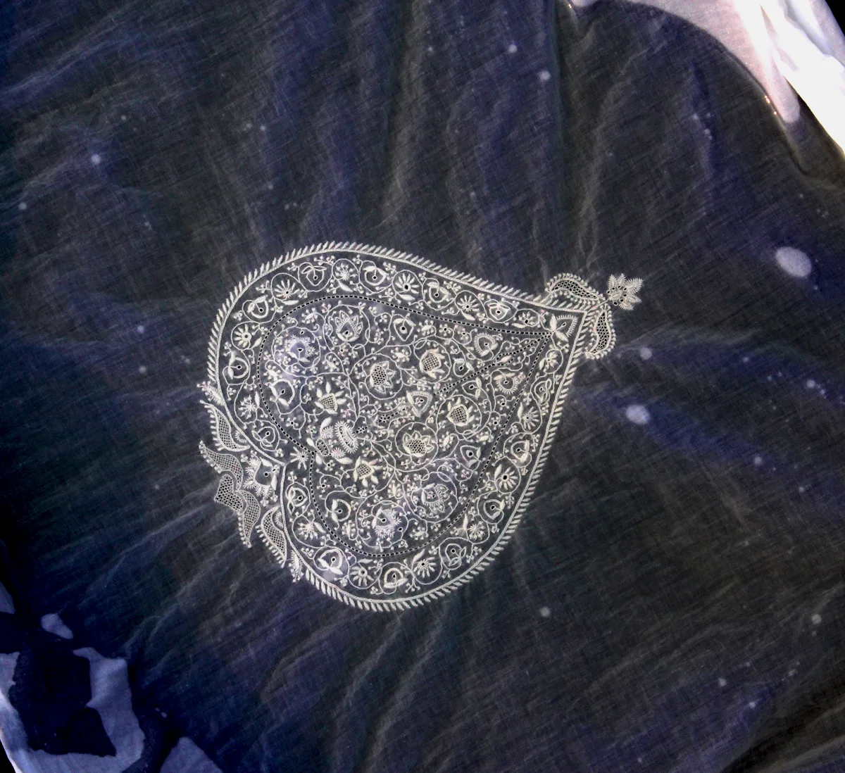Motif chikankari ancien du XVIIe siècle finement brodé en fil blanc sur tissu foncé, exemple de résultat traditionnel
