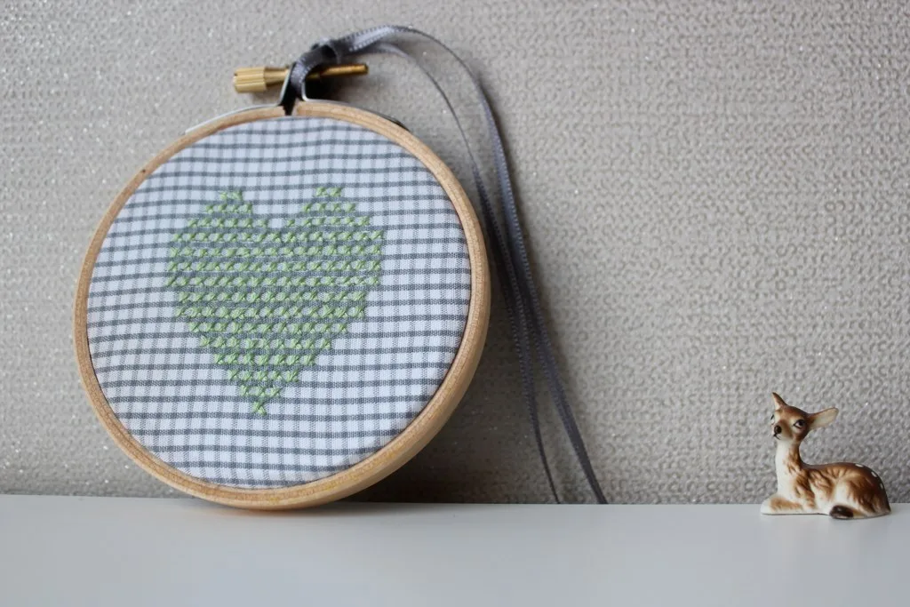 Petit cerceau brodé d'un cœur vert sur tissu à carreaux, exemple de décoration de Noël rapide à broder