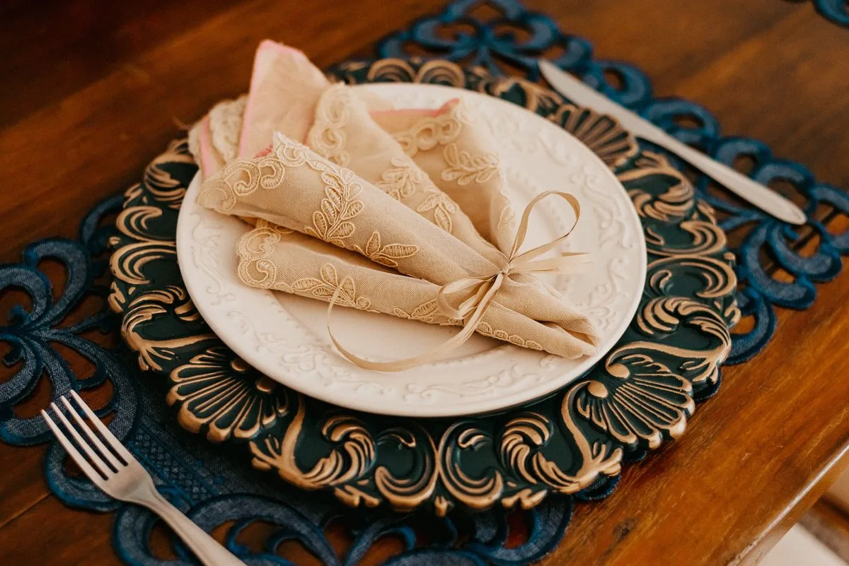 Serviette en dentelle brodée délicatement disposée sur une assiette pour une table de fêtes élégante