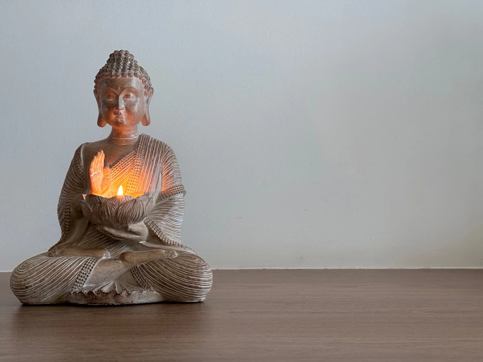 Statue de bouddha avec bougie allumée sur surface en bois — détail décoratif pour un espace zen et méditation