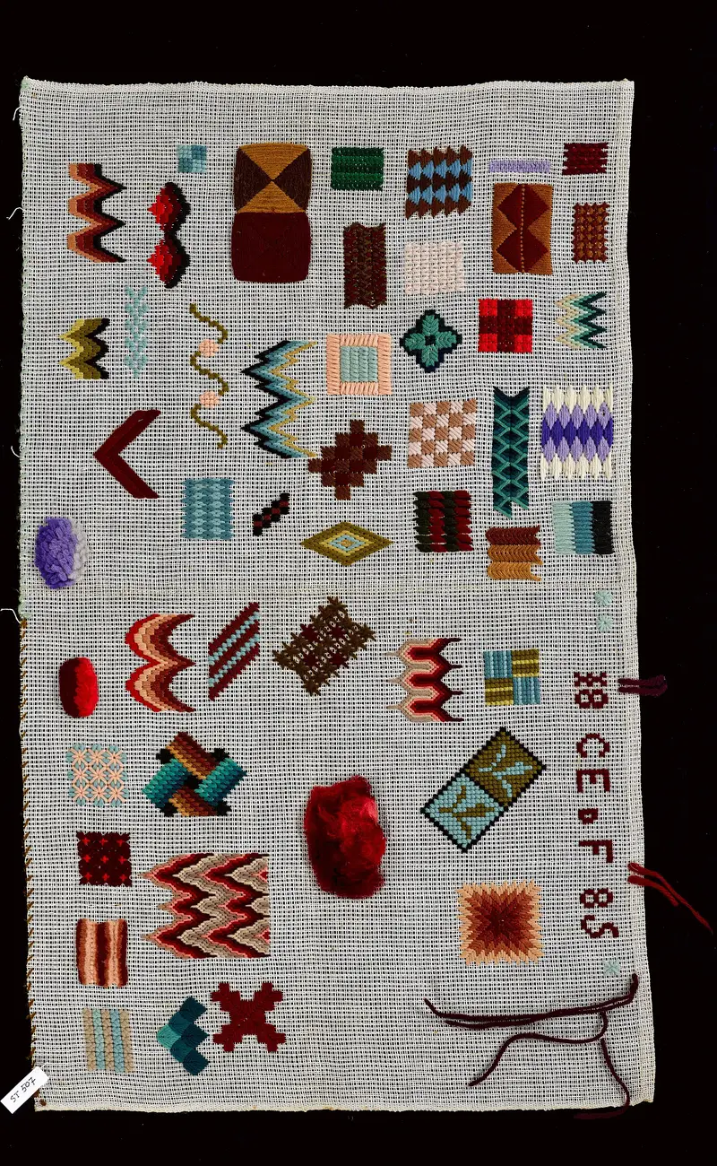 Échantillonnier de broderie inachevé de 1885 avec motifs géométriques colorés et fil encore accroché, conservé au MoMu d'Anvers