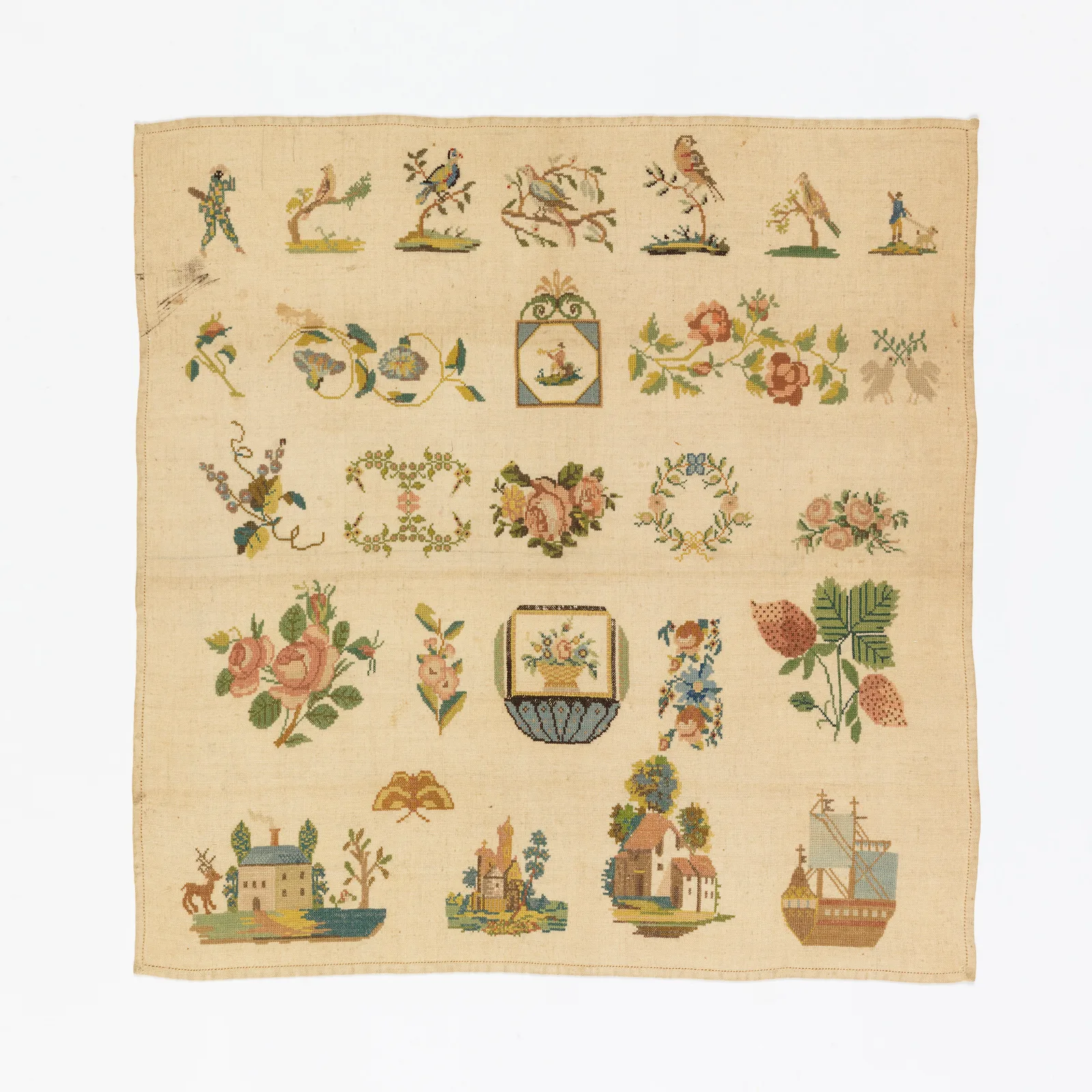 sampler brodé du XIXe siècle représentant fleurs oiseaux maisons et paysages en point de croix couleurs douces sur fond lin