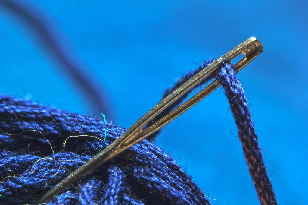 Aiguille et fil à broder bleu marine préparés pour un projet de cadeau naissance au point de croix