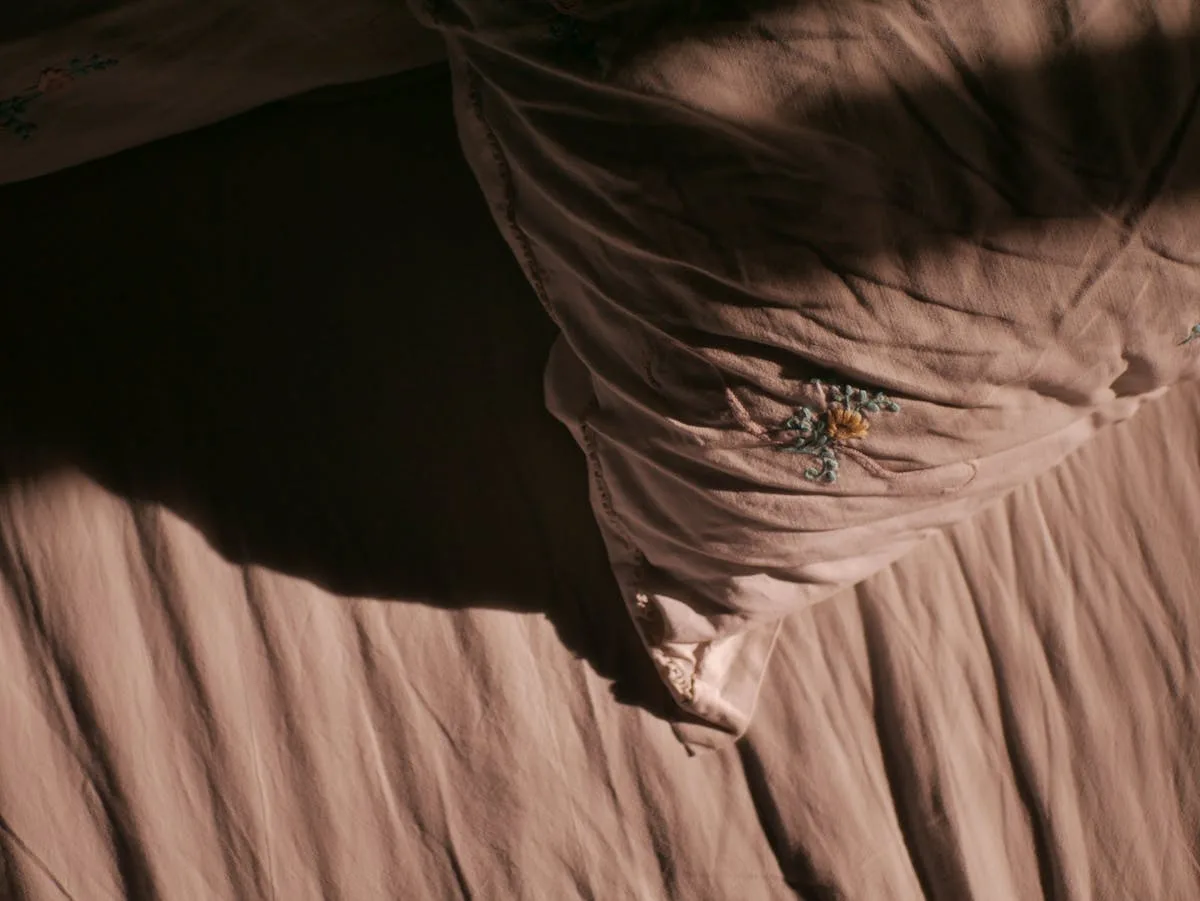 Détail d'une broderie florale sur textile de chambre — point de broderie sur tissu lin beige