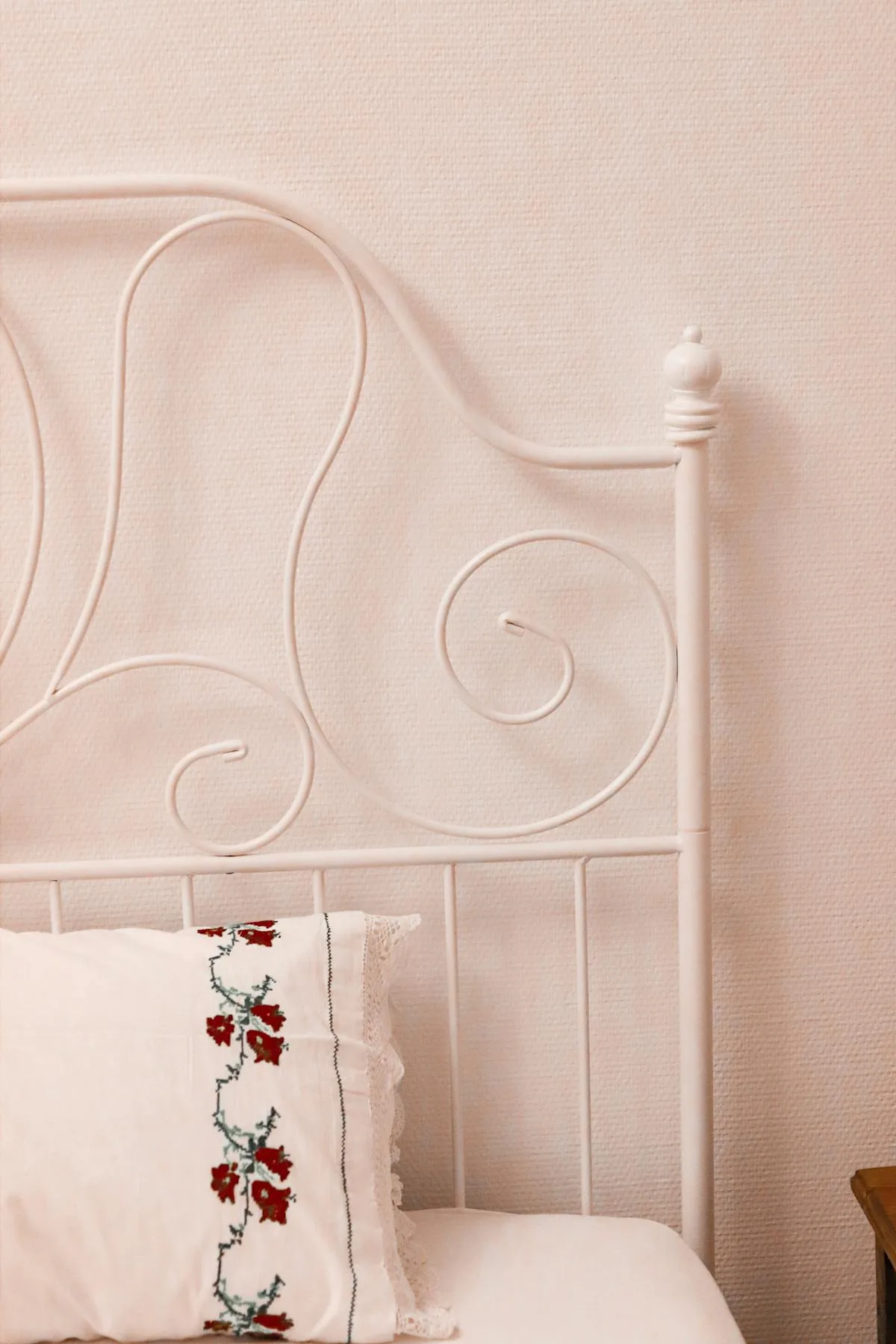 Lit fer forgé blanc avec taie d'oreiller brodée de fleurs rouges — chambre romantique au linge brodé