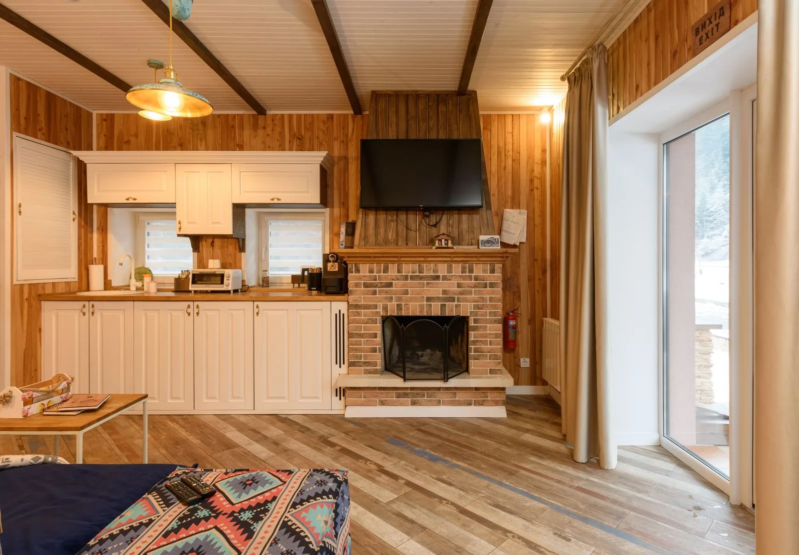 Intérieur rustique en bois avec cheminée en briques, ambiance maison de campagne chaleureuse propice aux textiles brodés