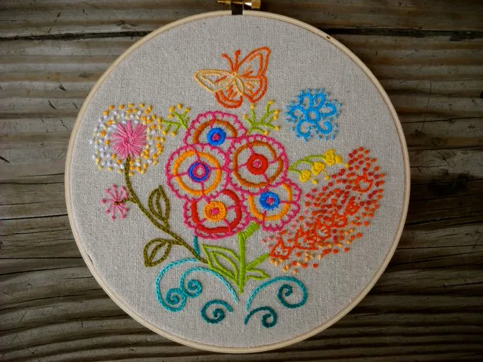 Tambour de broderie avec papillon et fleurs colorées en point de broderie