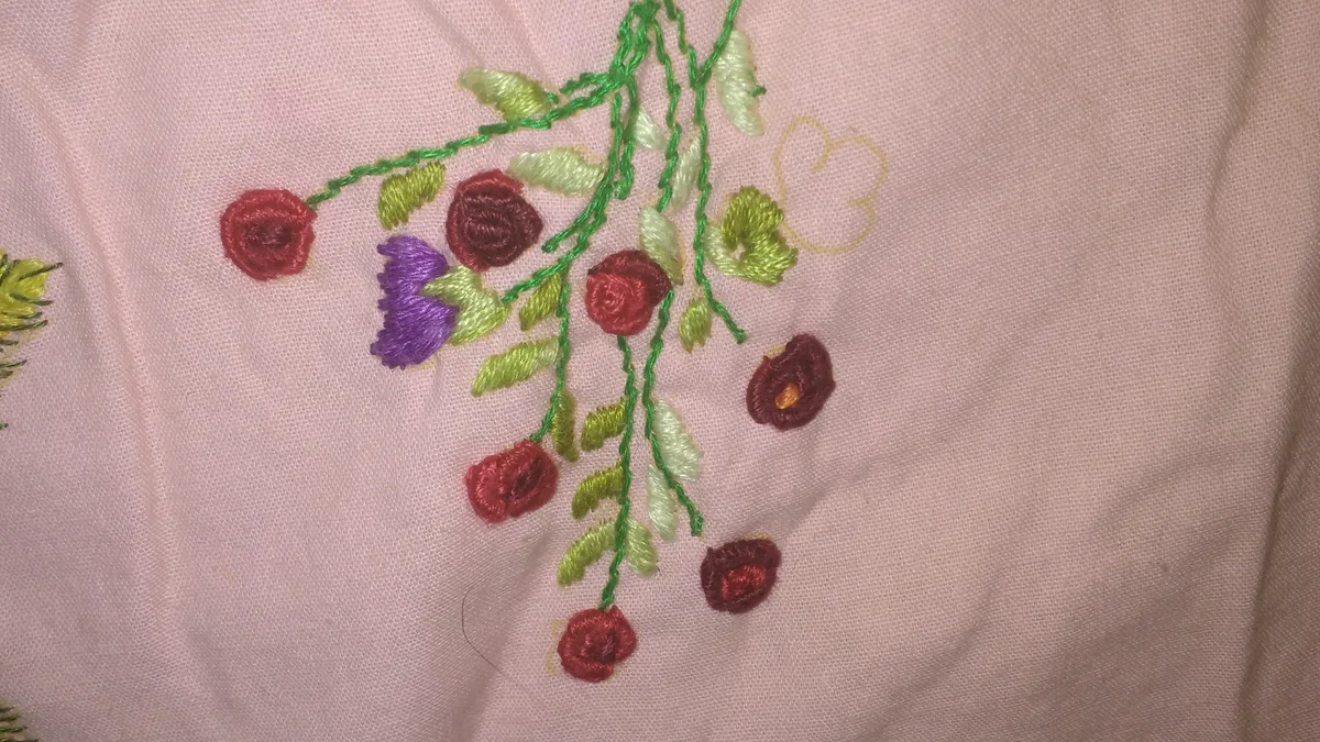 Broderie florale sur tissu rose avec tiges en point de tige et roses en point arrière