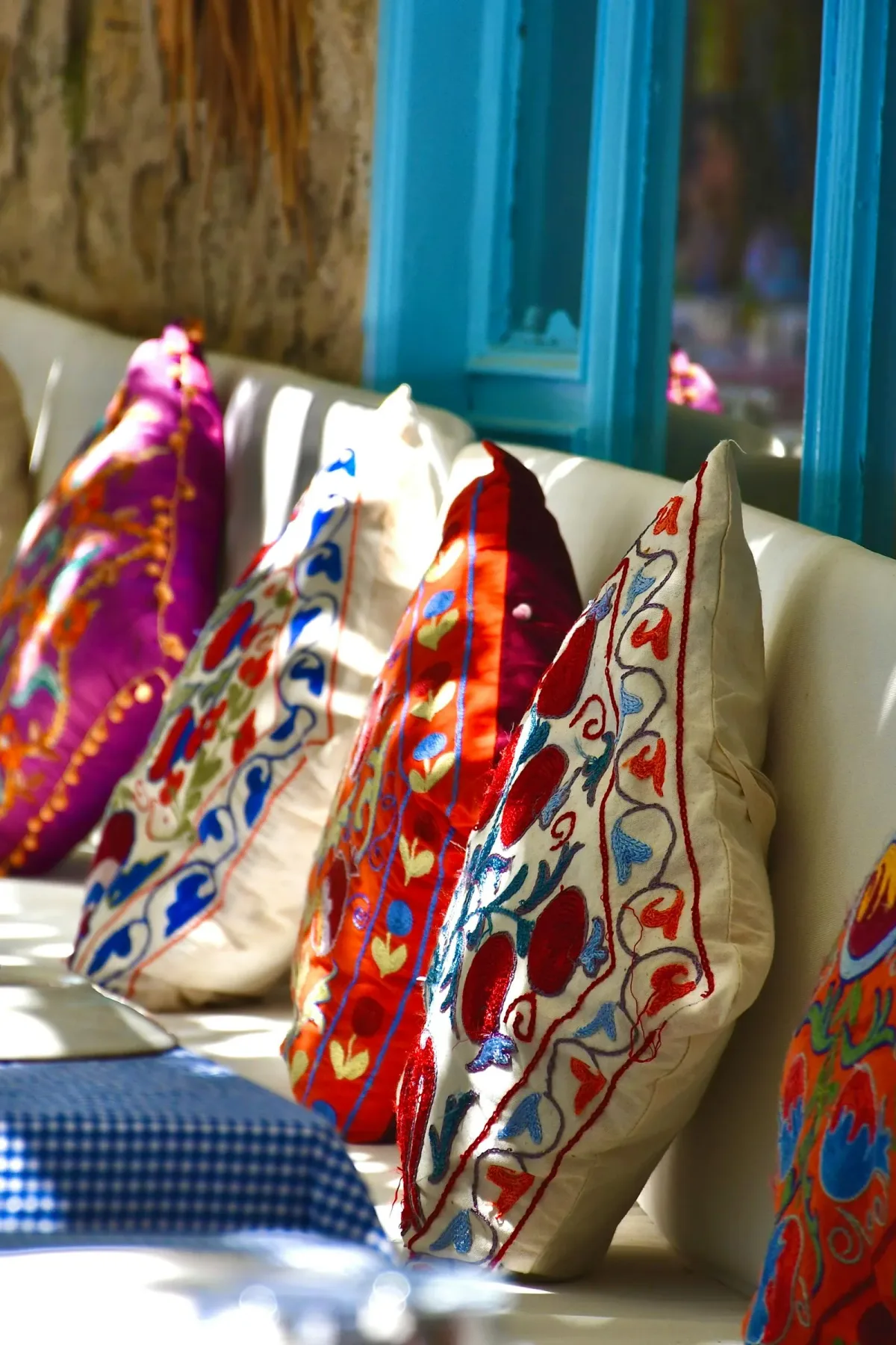 Coussins brodés colorés de style suzani disposés sur un canapé, ambiance méditerranéenne