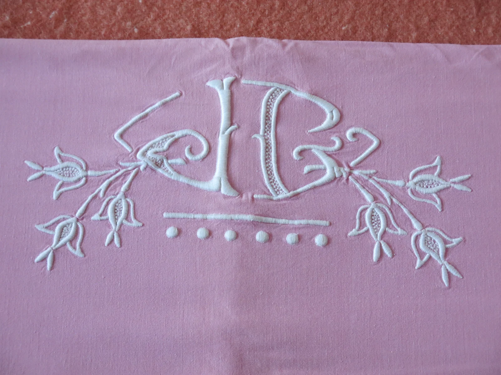Monogramme brodé en point de croix sur tissu rose, exemple de personnalisation pour trousse de rentrée