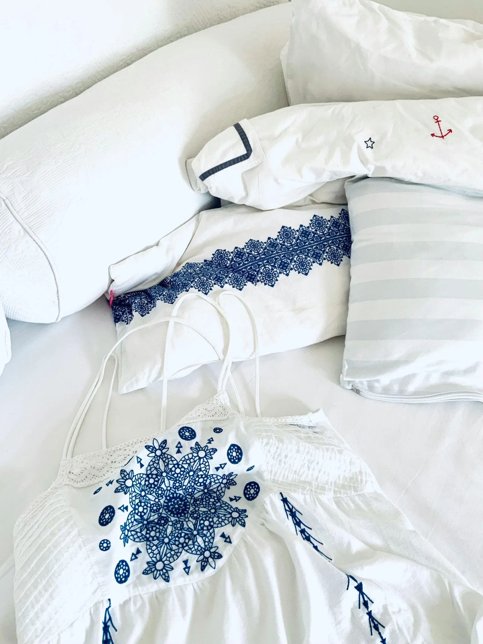 Linge de lit et de bain blanc avec broderie bleue en motifs floraux et géométriques — détail textile