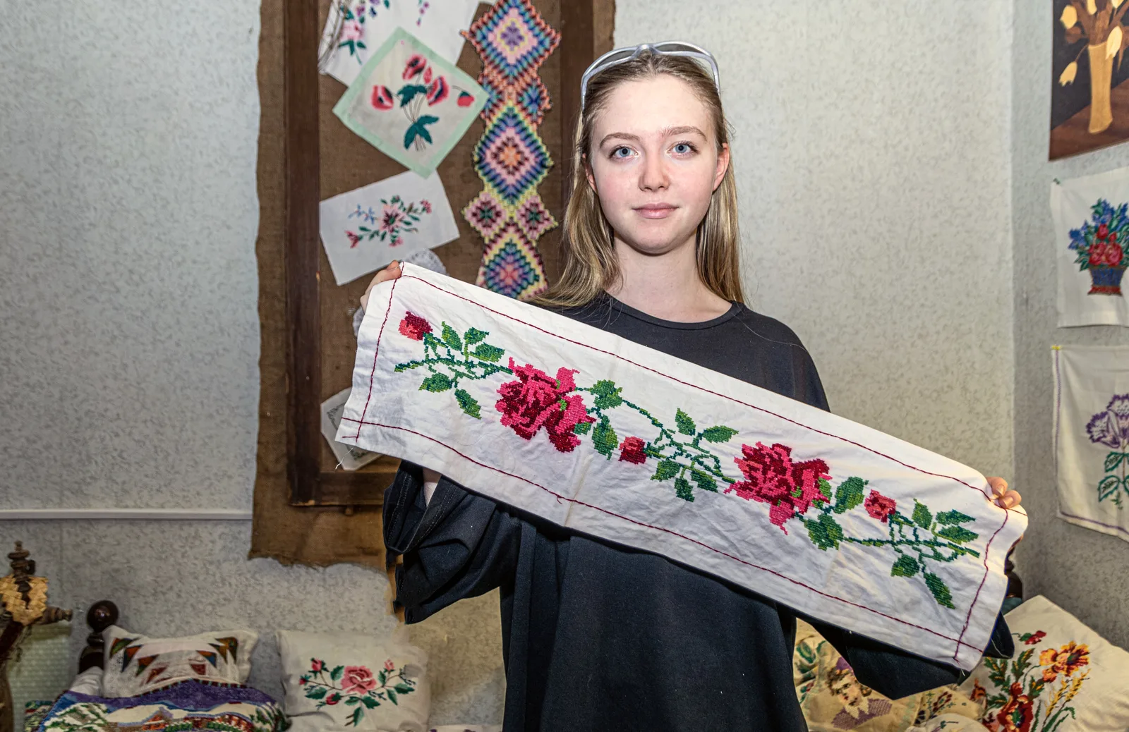 Jeune femme tenant un chemin de table brodé main en point de croix avec roses rouges sur lin blanc