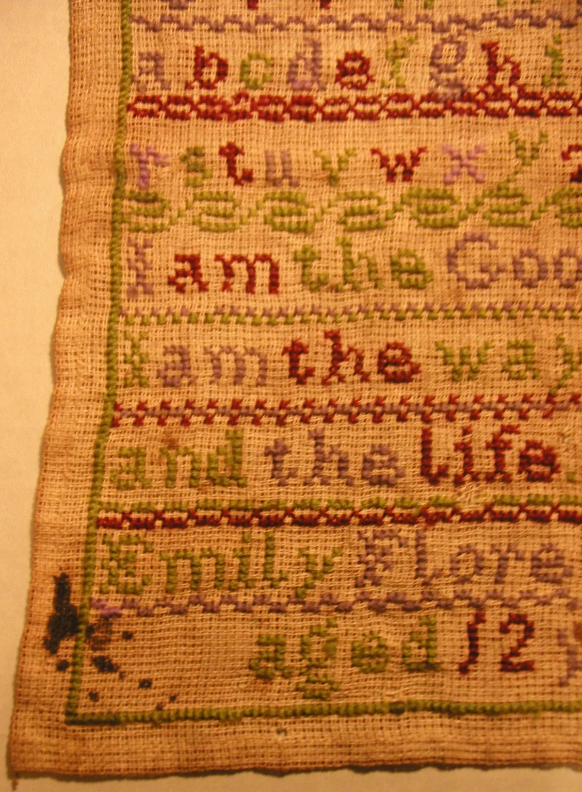 Détail d'un sampler en laine brodé au point de croix signé Emily Florence Redrup, âgée de 12 ans