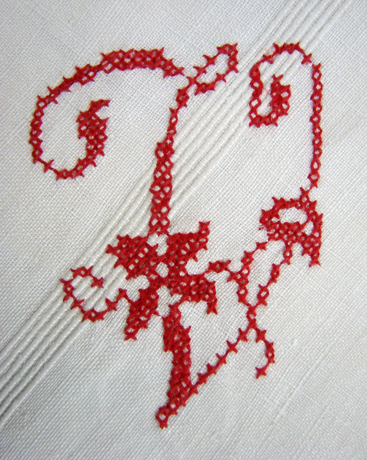 Lettre monogramme brodée au point de croix en fil rouge sur toile blanche