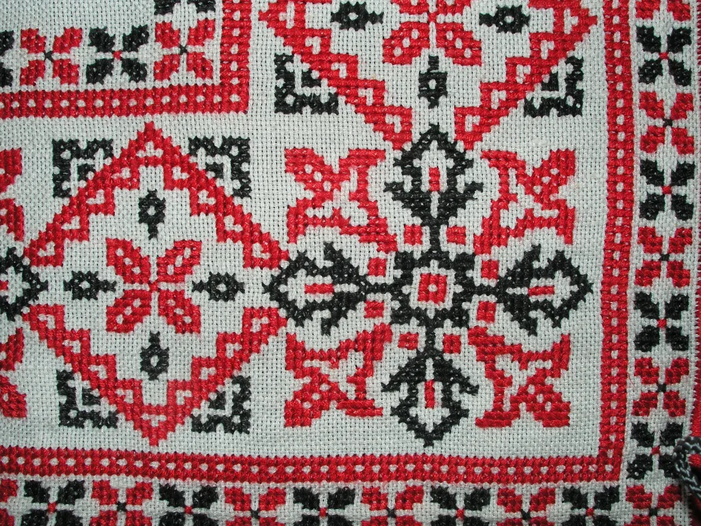 Grille de point de croix traditionnelle en fils rouge et noir, détail des croix brodées
